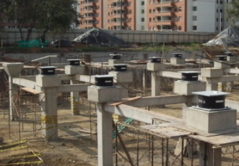 Photo of several seismic isolators at large construction site.